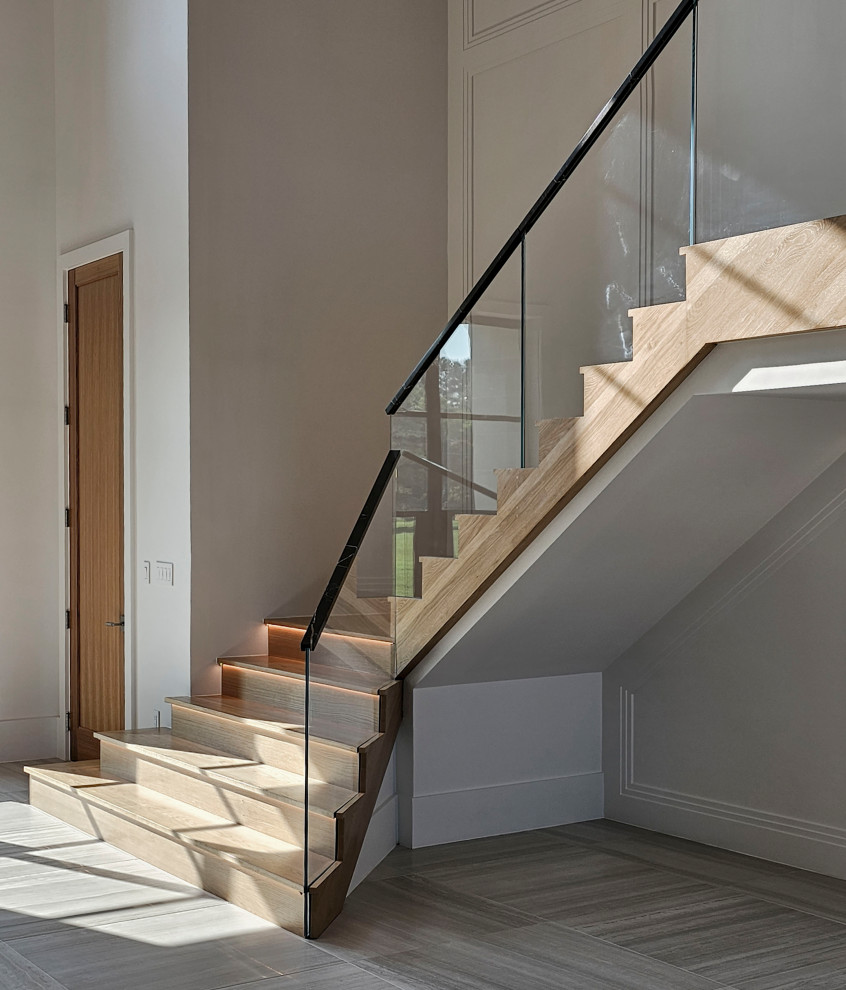 Стильный дизайн: огромная деревянная лестница на больцах в современном стиле с деревянными ступенями, перилами из смешанных материалов и панелями на стенах - последний тренд