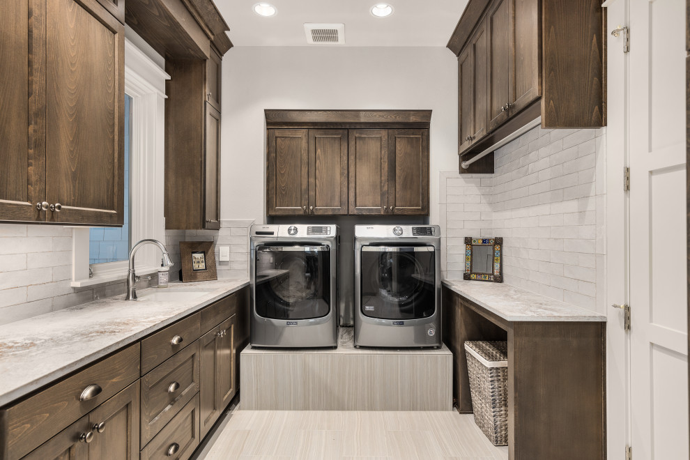 This is an example of a mid-sized transitional laundry room in Portland with an undermount sink, shaker cabinets, dark wood cabinets, quartz benchtops, white splashback, ceramic splashback, grey walls, porcelain floors, a side-by-side washer and dryer and multi-coloured benchtop.