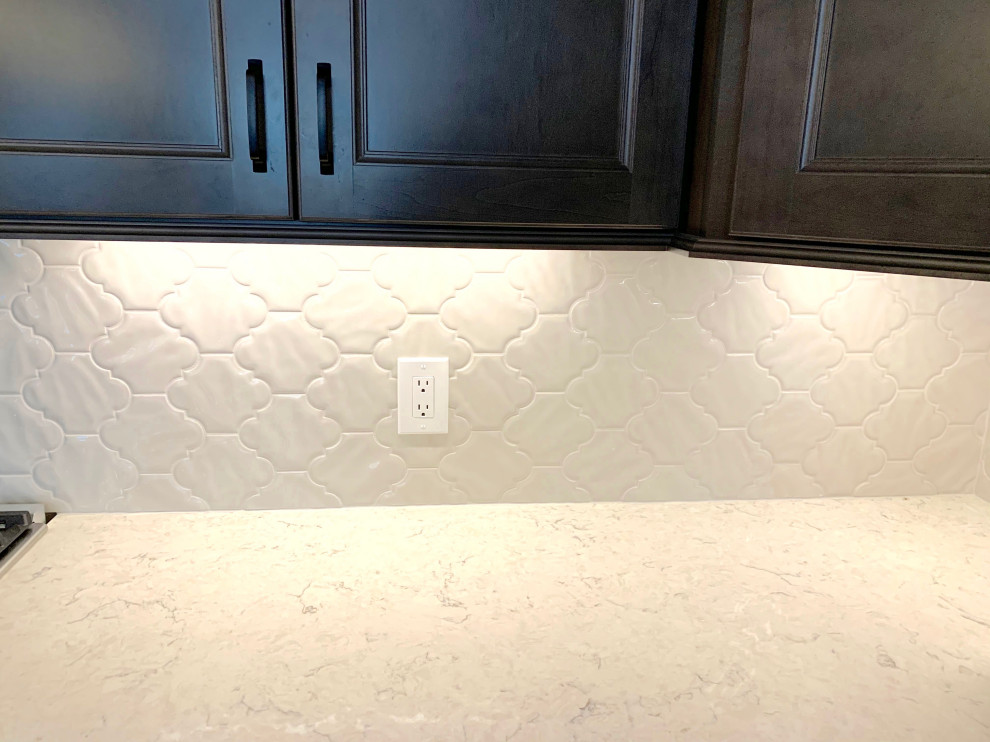 Eat-in kitchen - mid-sized transitional l-shaped medium tone wood floor and brown floor eat-in kitchen idea in Cincinnati with an undermount sink, recessed-panel cabinets, gray cabinets, quartz countertops, white backsplash, porcelain backsplash, stainless steel appliances, an island and white countertops