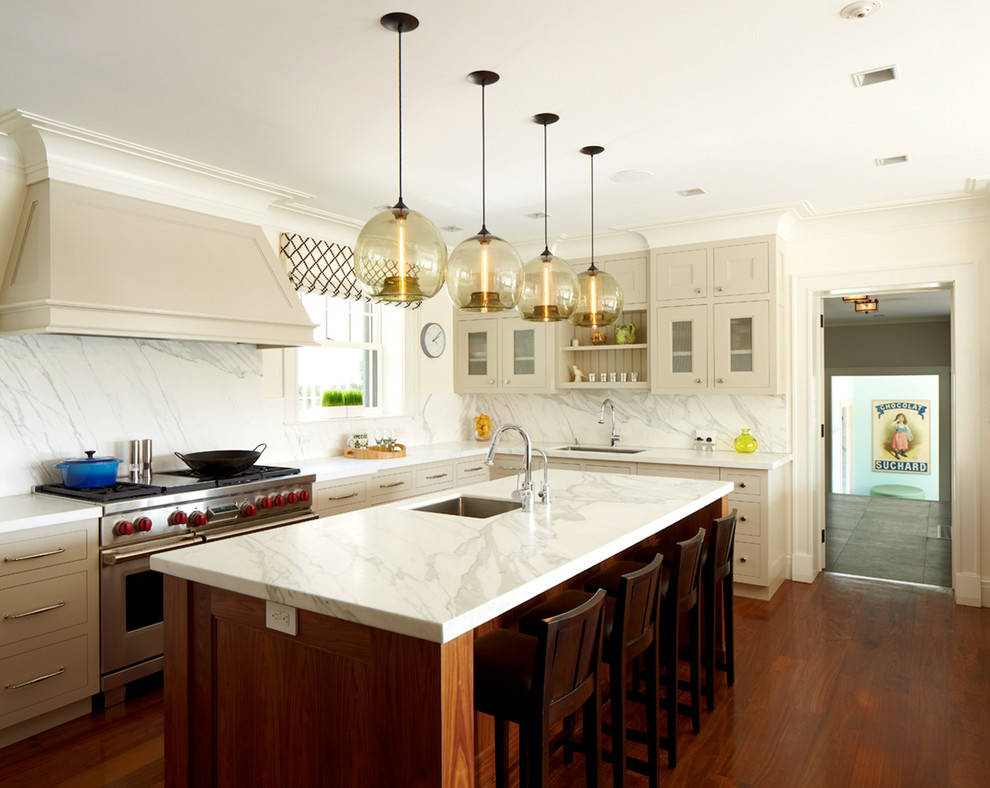 Transitional l-shaped eat-in kitchen in New York with glass-front cabinets, beige cabinets, marble benchtops, stainless steel appliances, dark hardwood floors, with island, white splashback and marble splashback.