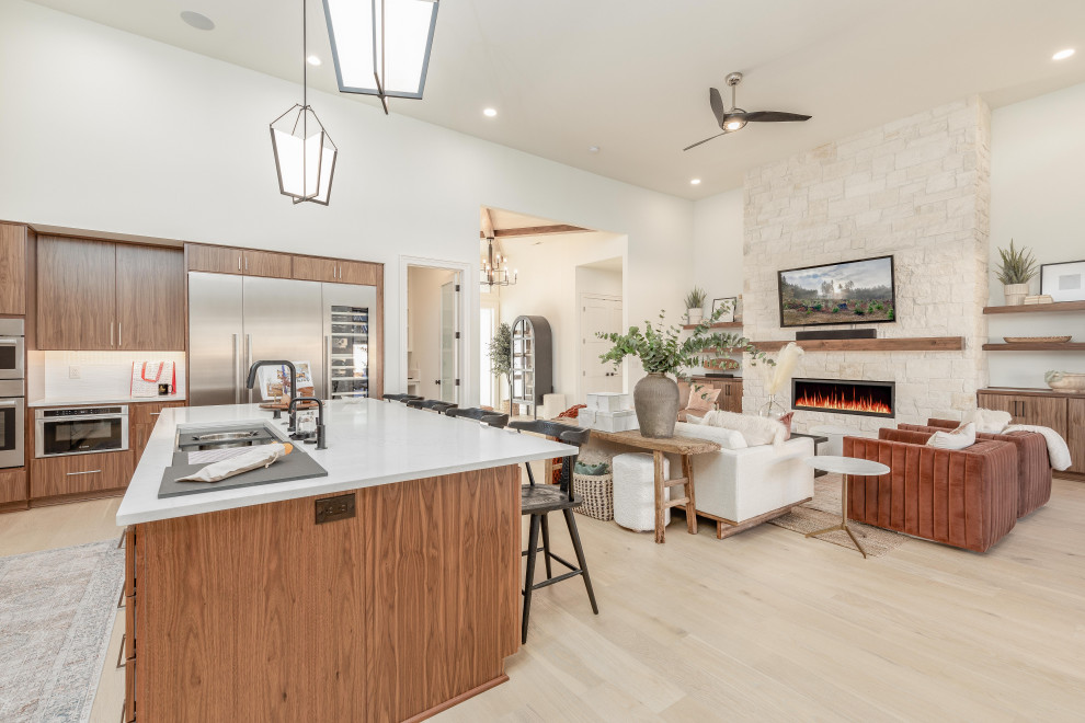 Photo of a mid-sized l-shaped open plan kitchen in Portland with an undermount sink, flat-panel cabinets, medium wood cabinets, quartzite benchtops, white splashback, ceramic splashback, stainless steel appliances, light hardwood floors, with island, brown floor and white benchtop.