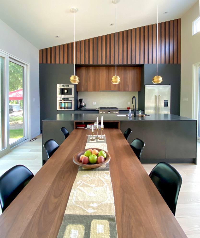 This is an example of a mid-sized modern eat-in kitchen in Toronto with flat-panel cabinets, dark wood cabinets, tile benchtops, beige splashback, light hardwood floors, with island and black benchtop.