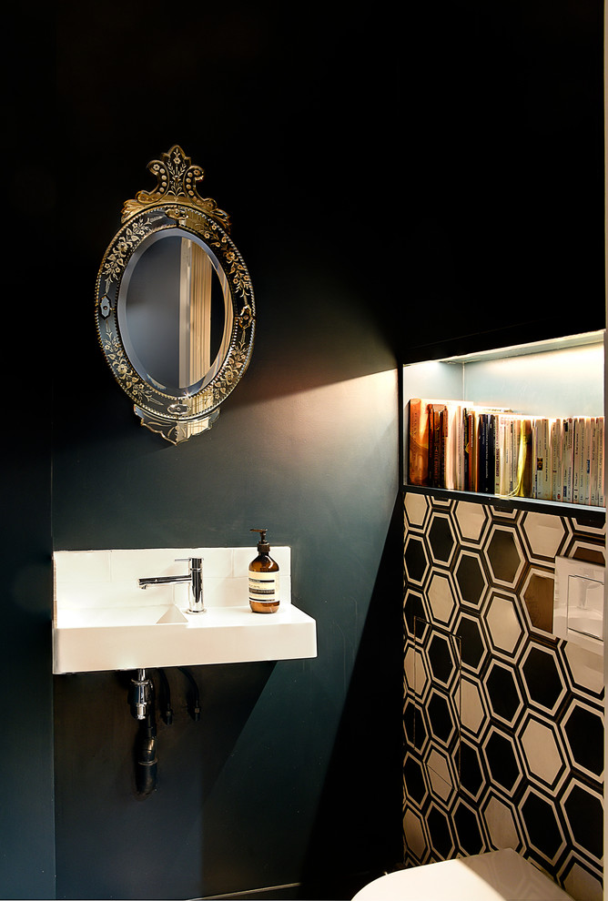 This is an example of a small transitional powder room in Paris with a wall-mount toilet, beige tile, blue tile, brown tile, blue walls, a wall-mount sink and white benchtops.