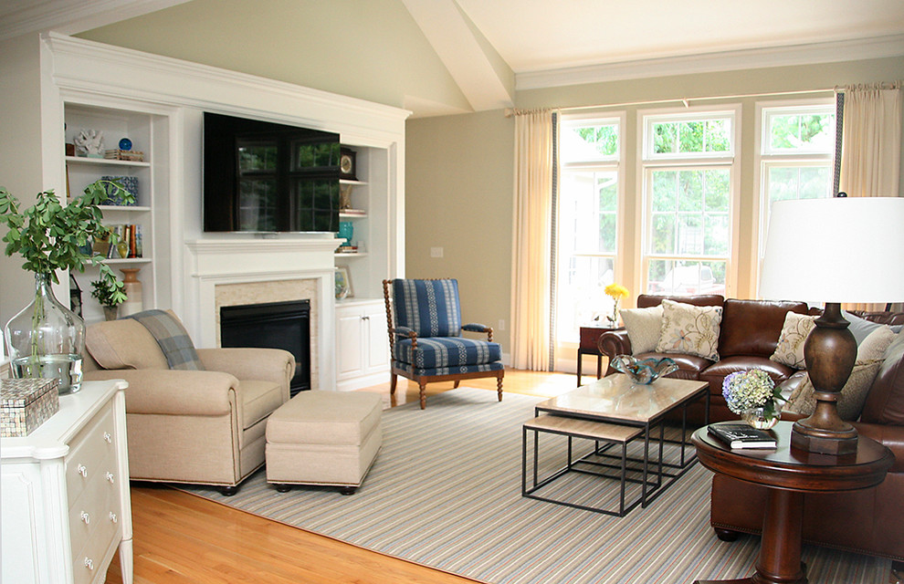 Photo of a mid-sized transitional open concept living room in Boston with beige walls, light hardwood floors, a standard fireplace, a stone fireplace surround, a wall-mounted tv and brown floor.