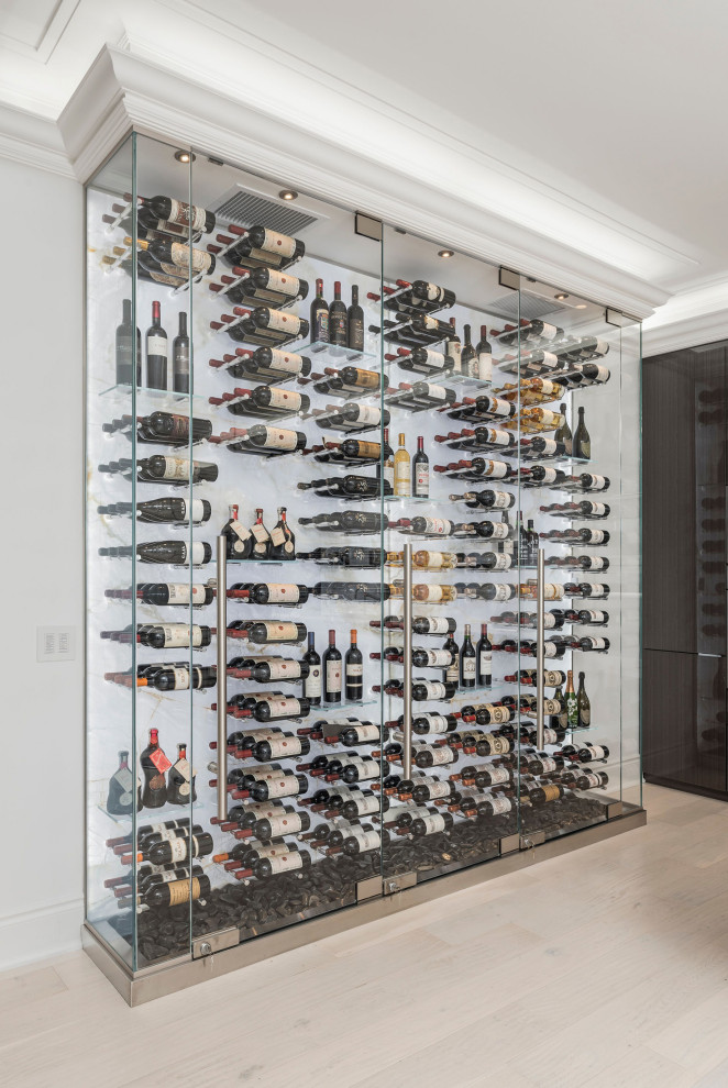 This is an example of a mid-sized modern wine cellar in Toronto with light hardwood floors, display racks and beige floor.