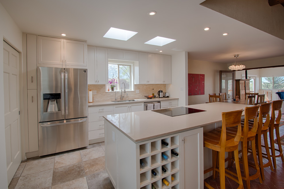 Mid-sized transitional l-shaped porcelain tile and beige floor eat-in kitchen photo in Albuquerque with an undermount sink, shaker cabinets, white cabinets, quartzite countertops, beige backsplash, stone tile backsplash, stainless steel appliances, an island and beige countertops
