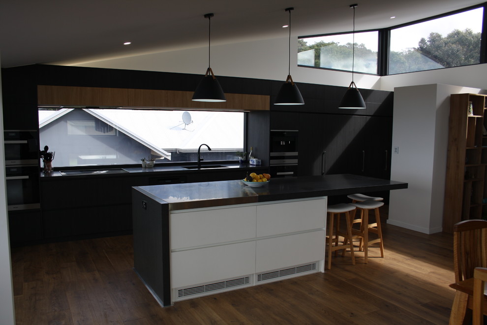 Inspiration for a large modern galley kitchen in Other with an undermount sink, flat-panel cabinets, dark wood cabinets, quartz benchtops, window splashback, stainless steel appliances, with island and black benchtop.