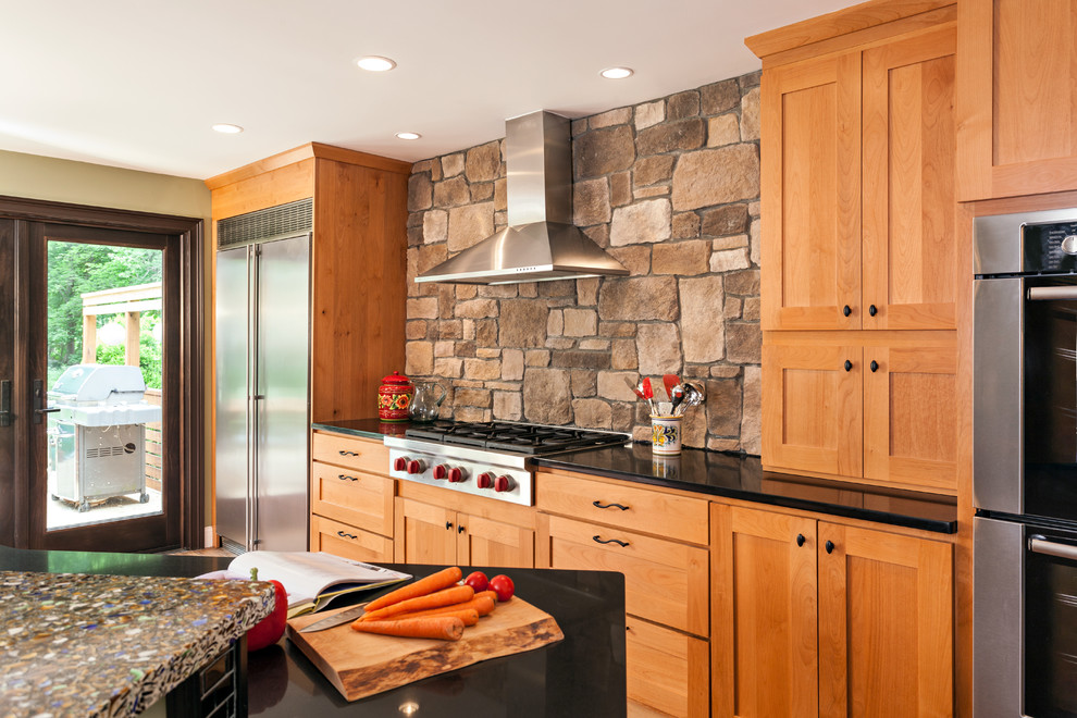 Example of a mid-sized transitional u-shaped bamboo floor eat-in kitchen design in Boston with shaker cabinets, medium tone wood cabinets, recycled glass countertops, brown backsplash, an island, an undermount sink, stone tile backsplash, stainless steel appliances and green walls