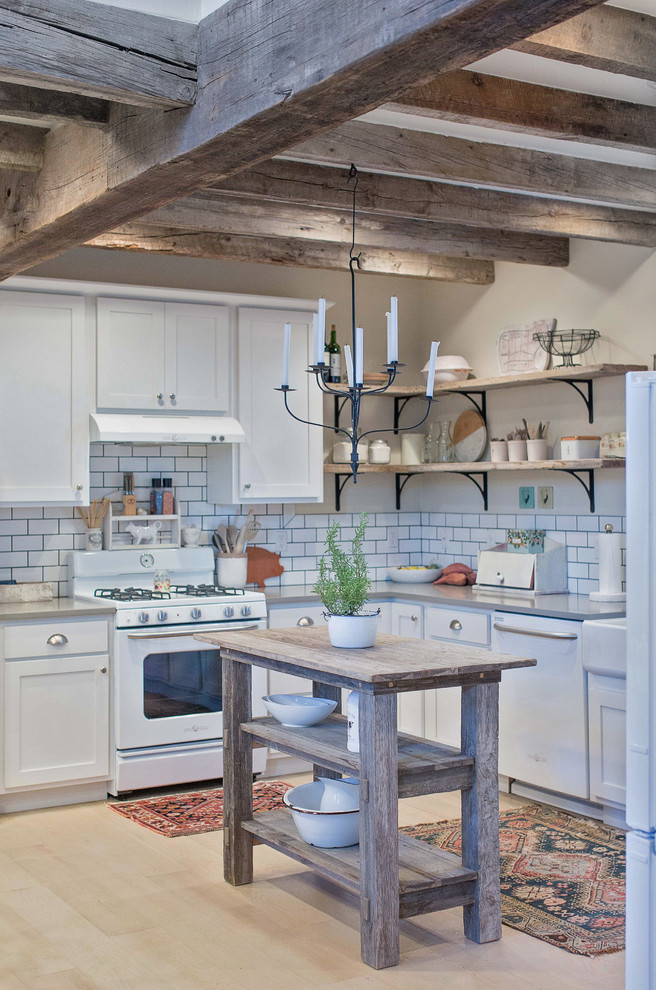 Inspiration for a country kitchen in Chicago with a farmhouse sink, shaker cabinets, white splashback, subway tile splashback, white appliances, light hardwood floors, no island and white cabinets.