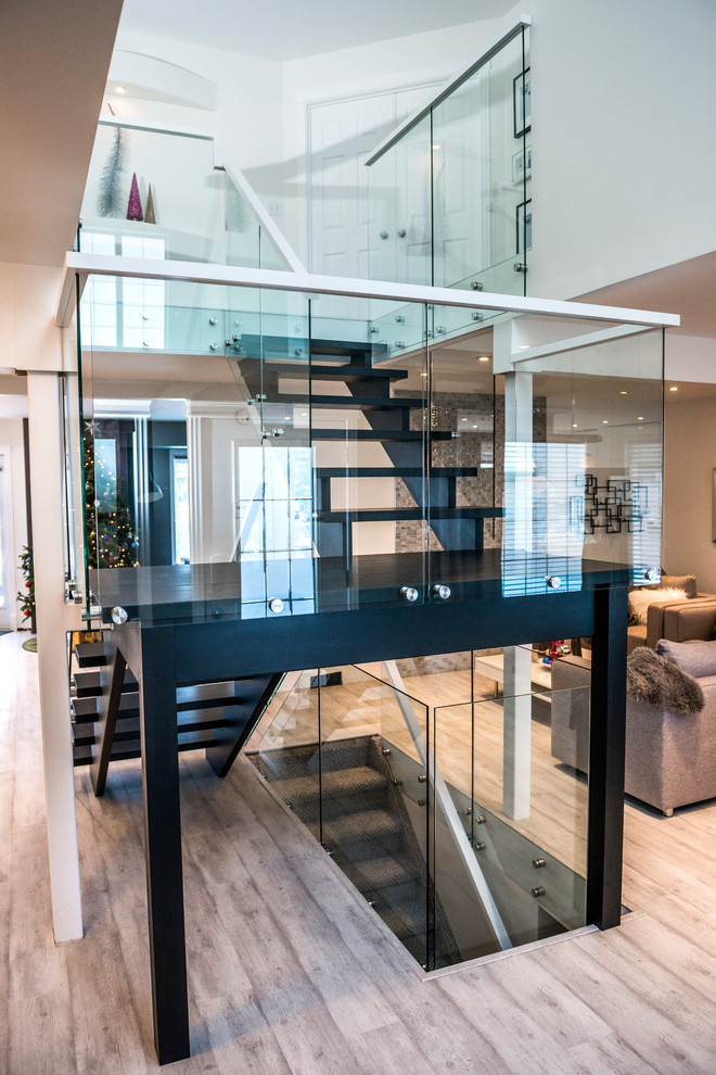 Photo of a mid-sized contemporary wood u-shaped staircase in Other with open risers and glass railing.