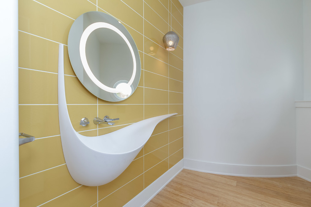 This is an example of a mid-sized contemporary powder room in Other with yellow tile, ceramic tile, white walls, light hardwood floors, a wall-mount sink and beige floor.