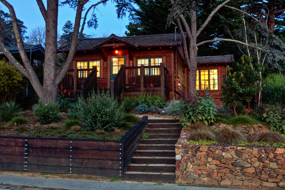 Small country one-storey brown house exterior in San Francisco with wood siding, a gable roof and a tile roof.