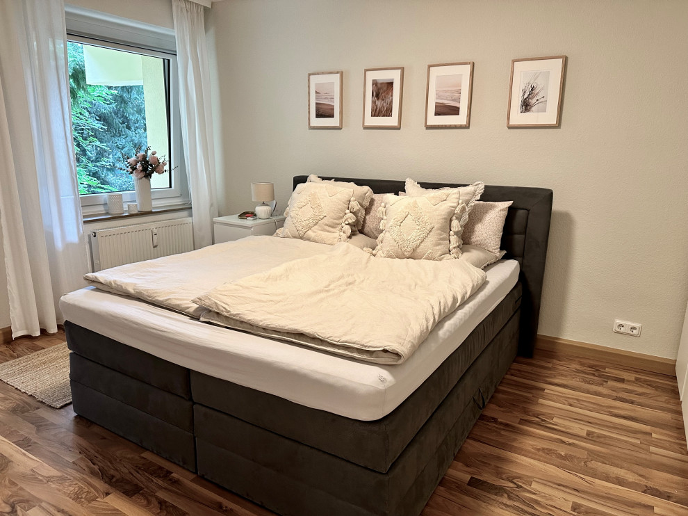 На фото: хозяйская, серо-белая спальня среднего размера в современном стиле с бежевыми стенами, полом из ламината, коричневым полом и потолком с обоями с