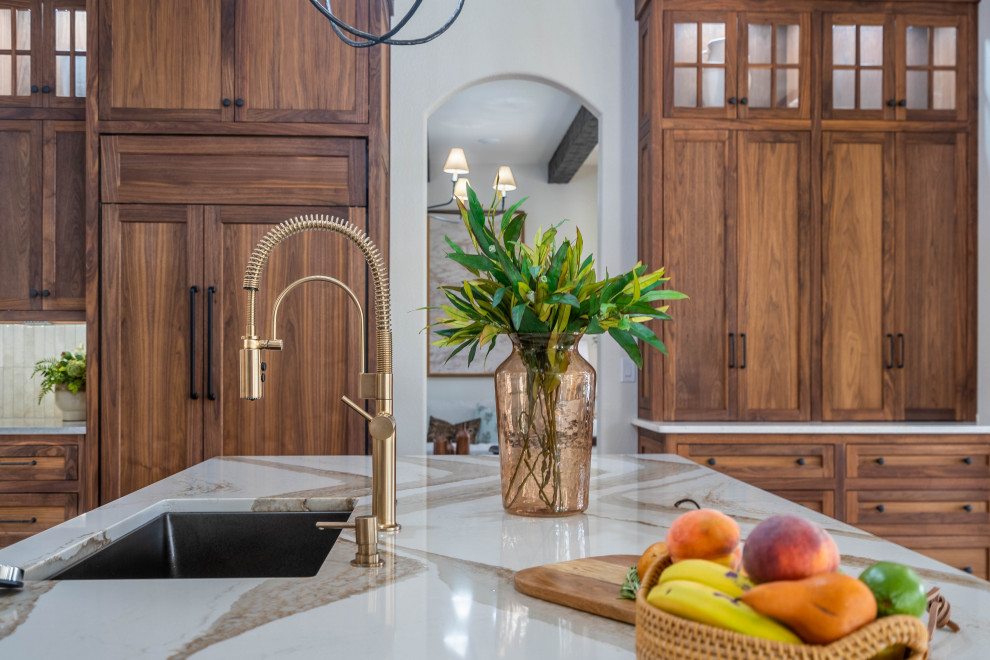 Example of a huge transitional l-shaped light wood floor and beige floor open concept kitchen design with an undermount sink, shaker cabinets, dark wood cabinets, quartz countertops, beige backsplash, subway tile backsplash, paneled appliances, an island and brown countertops