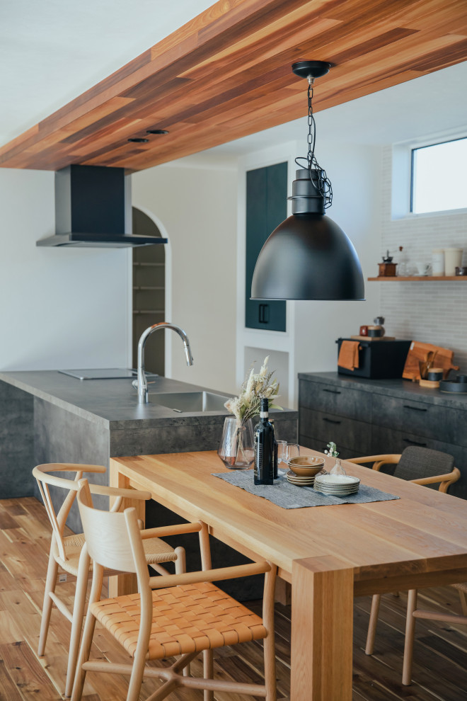This is an example of a contemporary single-wall open plan kitchen in Other with black cabinets, medium hardwood flooring, beige floors, black worktops and a wood ceiling.