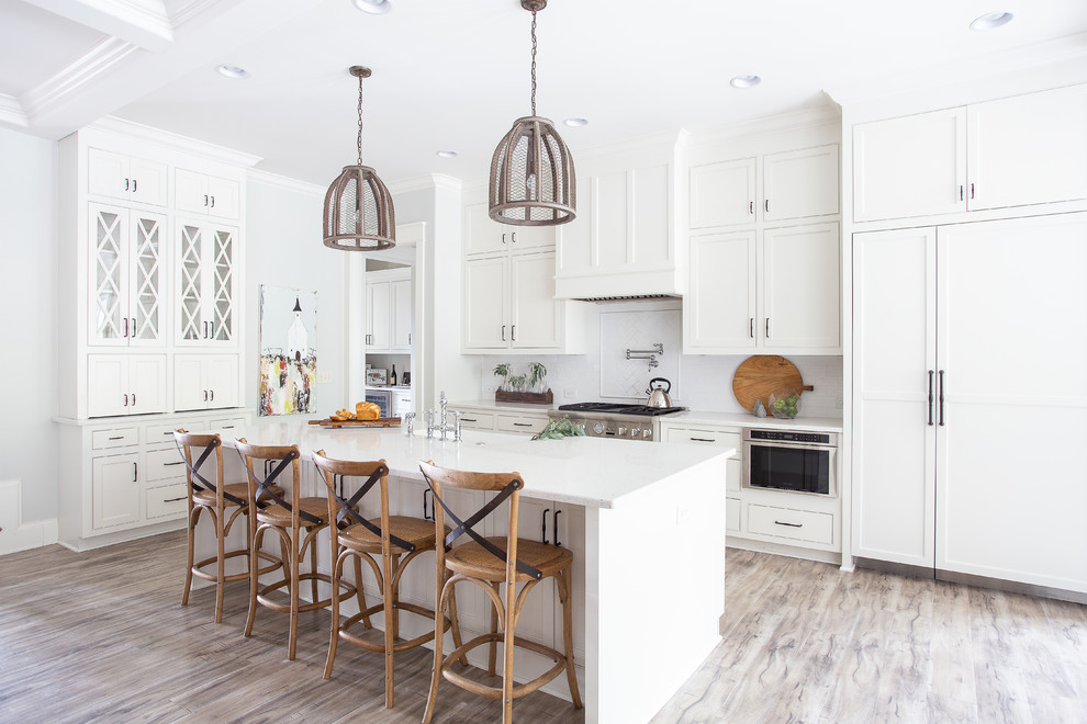 This is an example of a country u-shaped kitchen in Nashville with shaker cabinets, white cabinets, white appliances, with island and white benchtop.