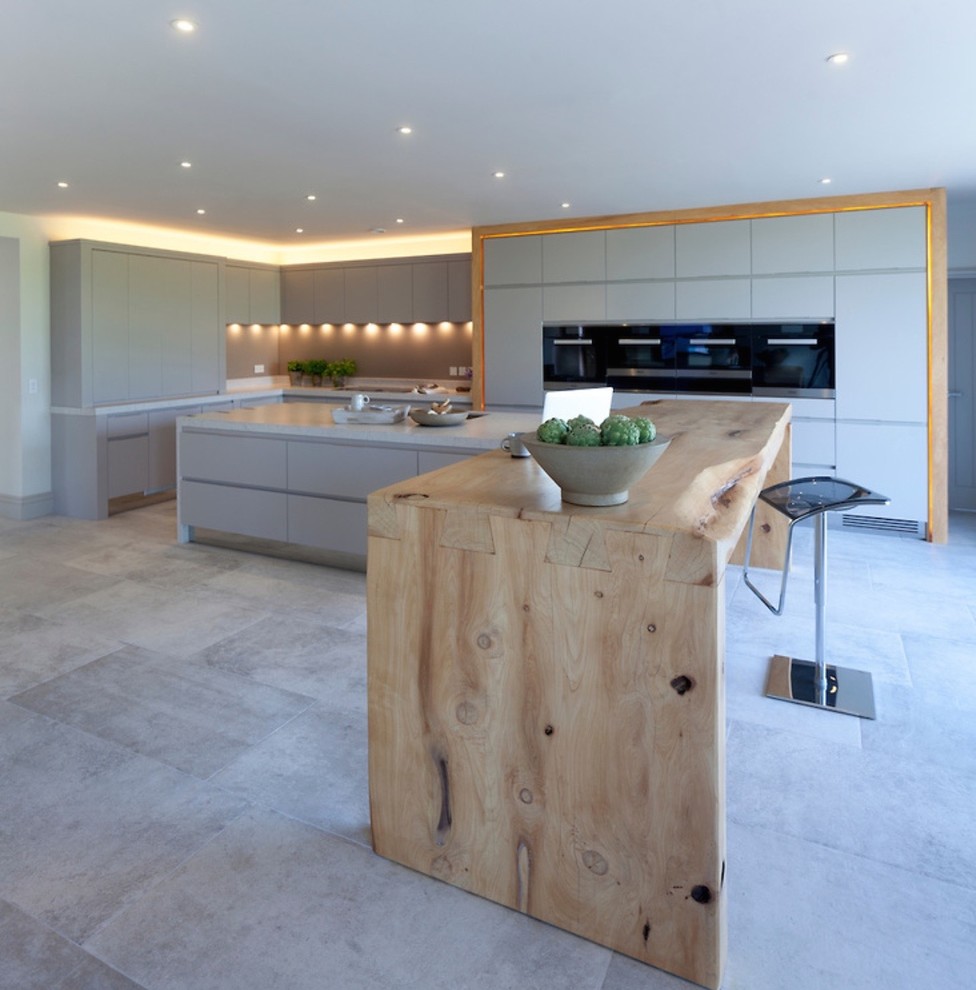 Expansive contemporary open plan kitchen in Cheshire with a double-bowl sink, flat-panel cabinets, grey cabinets, quartzite benchtops, grey splashback, glass sheet splashback, stainless steel appliances, porcelain floors and multiple islands.