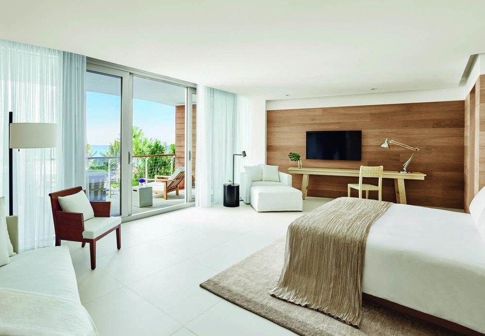 This is an example of a large beach style master bedroom in Toronto with white walls and white floor.