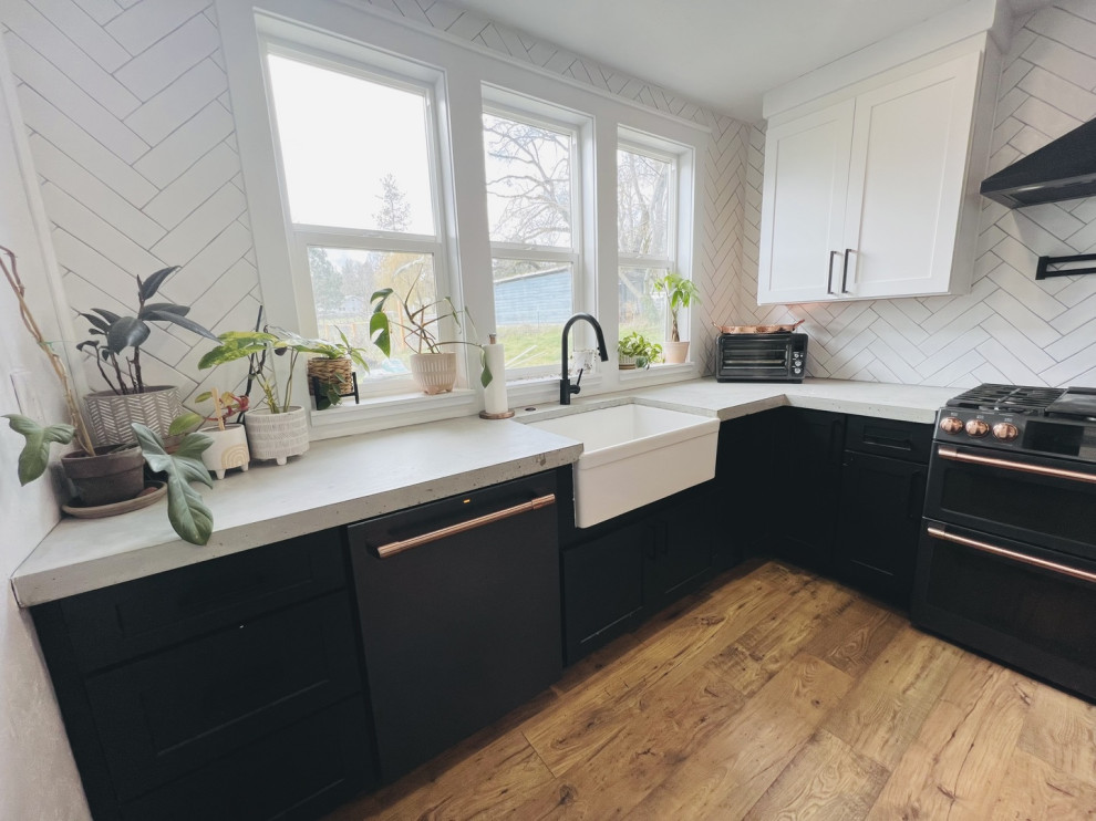 This is an example of a mid-sized traditional l-shaped eat-in kitchen with a farmhouse sink, shaker cabinets, black cabinets, quartzite benchtops, white splashback, ceramic splashback, black appliances, bamboo floors, no island, brown floor and white benchtop.