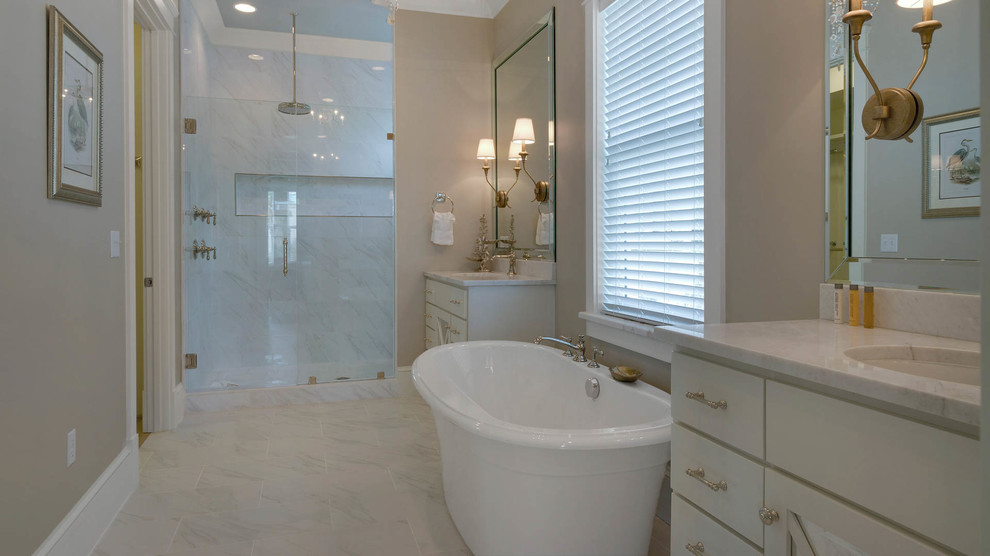Large beach style master bathroom in Miami with flat-panel cabinets, white cabinets, a freestanding tub, white tile, stone slab, beige walls, porcelain floors, an undermount sink, marble benchtops and an alcove shower.