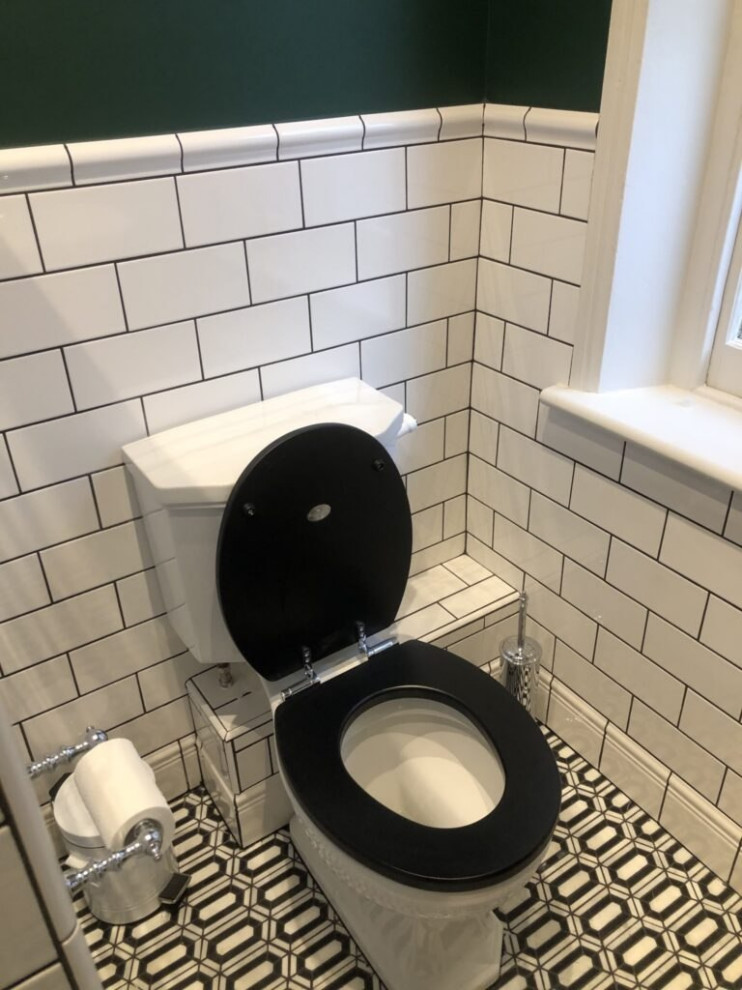 Medium sized cream and black family bathroom in London with open cabinets, white cabinets, a built-in bath, a shower/bath combination, a one-piece toilet, black and white tiles, ceramic tiles, white walls, ceramic flooring, a built-in sink, stainless steel worktops, black floors, a hinged door, grey worktops, feature lighting, a single sink, a freestanding vanity unit, a wood ceiling and wainscoting.