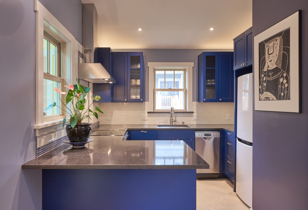 This is an example of a small transitional kitchen in Seattle with an undermount sink, flat-panel cabinets, blue cabinets, quartz benchtops, white splashback, subway tile splashback, porcelain floors, blue benchtop and stainless steel appliances.