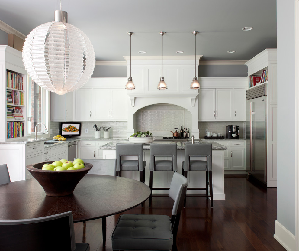 Photo of a transitional l-shaped eat-in kitchen in Detroit with stainless steel appliances, shaker cabinets, white cabinets and white splashback.