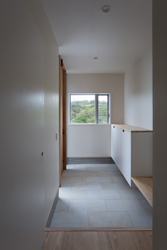 Inspiration for a porcelain tile entry hall remodel with white walls and a light wood front door