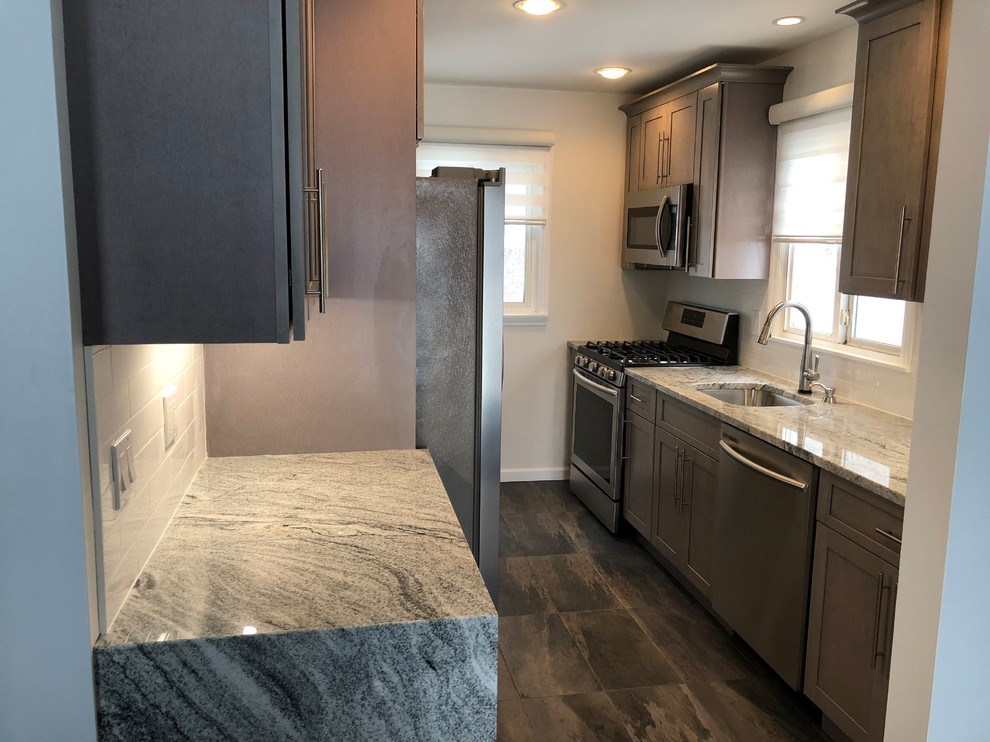 Example of a small minimalist galley porcelain tile and gray floor enclosed kitchen design in New York with an undermount sink, shaker cabinets, gray cabinets, granite countertops, white backsplash, ceramic backsplash, stainless steel appliances and no island
