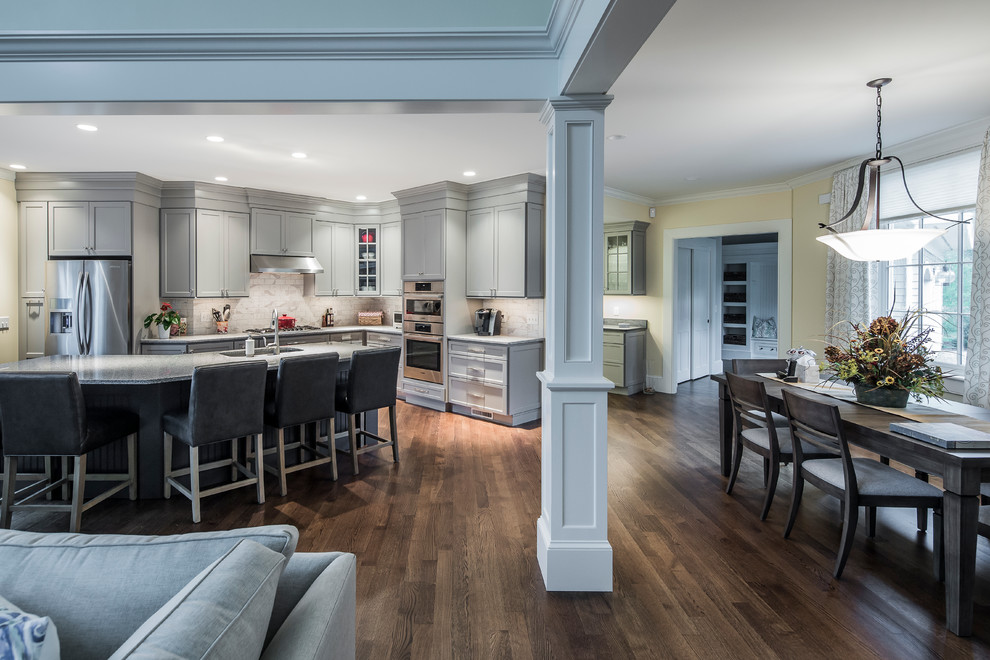Large transitional single-wall dark wood floor eat-in kitchen photo in Boston with an undermount sink, flat-panel cabinets, gray cabinets, granite countertops, white backsplash, ceramic backsplash, stainless steel appliances and an island