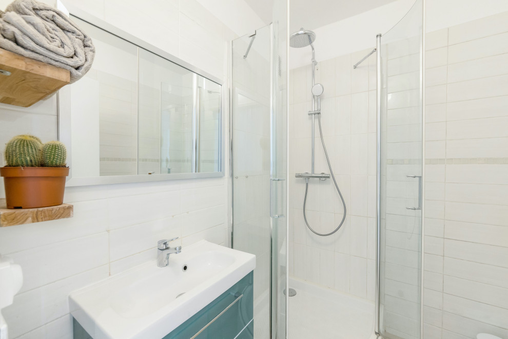 This is an example of a small modern 3/4 bathroom in Marseille with green cabinets, a corner shower, white tile, ceramic tile, white walls, a wall-mount sink, a hinged shower door, a single vanity and a floating vanity.