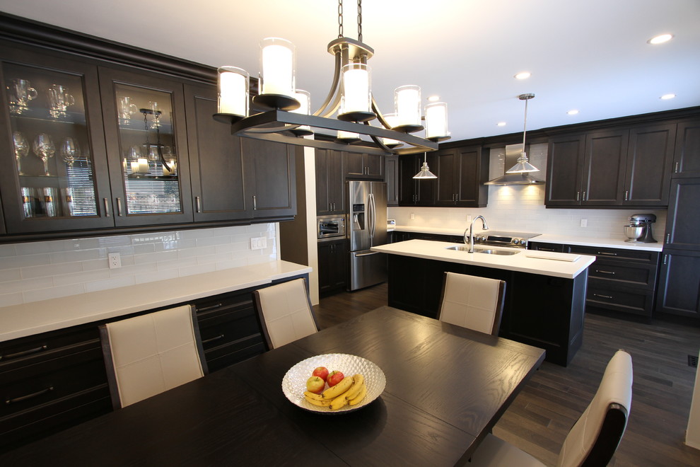 Design ideas for a large contemporary l-shaped eat-in kitchen in Toronto with an undermount sink, recessed-panel cabinets, dark wood cabinets, quartz benchtops, white splashback, glass tile splashback, stainless steel appliances, dark hardwood floors, with island and grey floor.