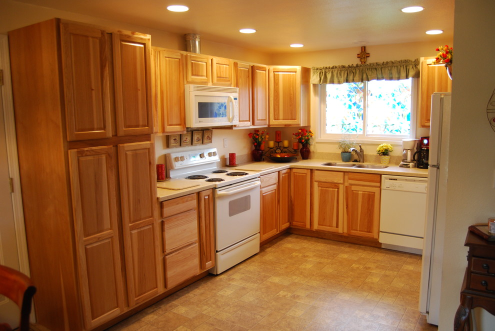 Photo of a mid-sized traditional u-shaped separate kitchen in Portland with a double-bowl sink, raised-panel cabinets, light wood cabinets, wood benchtops, white appliances, vinyl floors and no island.