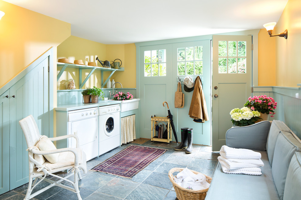 Photo of a country utility room in Other with a farmhouse sink, open cabinets, yellow walls and a side-by-side washer and dryer.