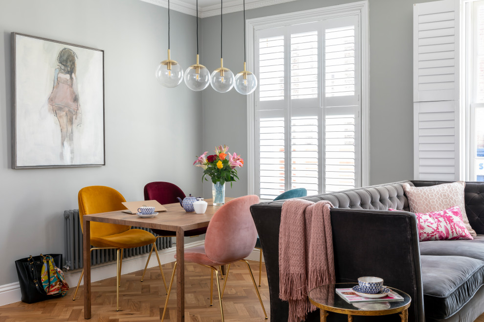 Eclectic dining room in London with grey walls, medium hardwood floors and brown floor.