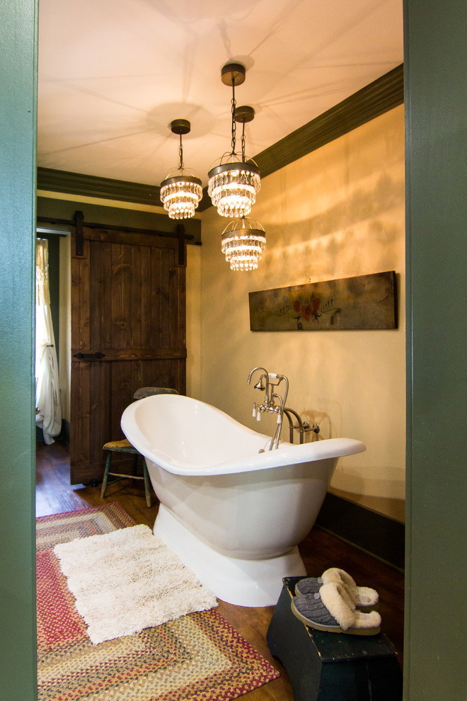 Freestanding bathtub - large rustic master medium tone wood floor freestanding bathtub idea with furniture-like cabinets, beige cabinets, a two-piece toilet, beige walls, an undermount sink, solid surface countertops and a hinged shower door