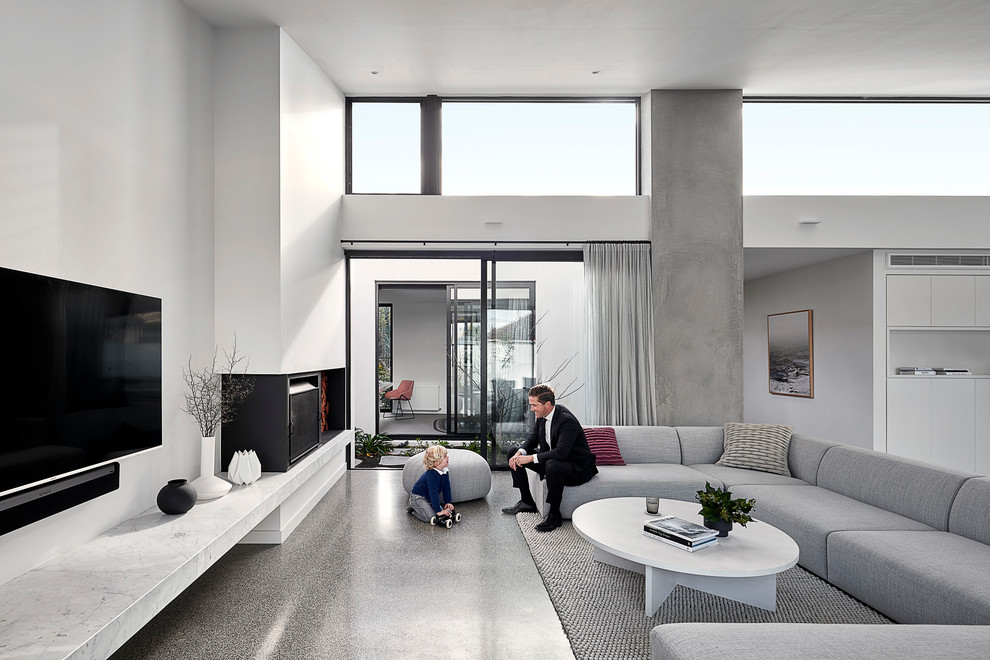 Large contemporary formal open concept living room in Melbourne with white walls, concrete floors, a standard fireplace, a metal fireplace surround, a wall-mounted tv and grey floor.
