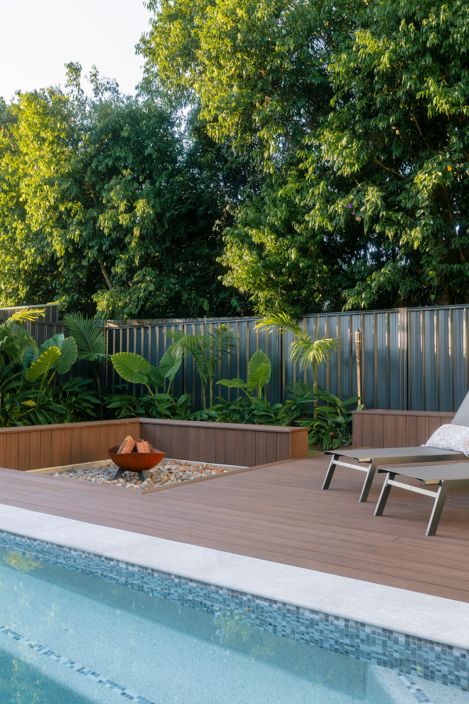 Inspiration for a mid-sized tropical backyard and first floor deck in Gold Coast - Tweed with a fire feature, no cover and glass railing.