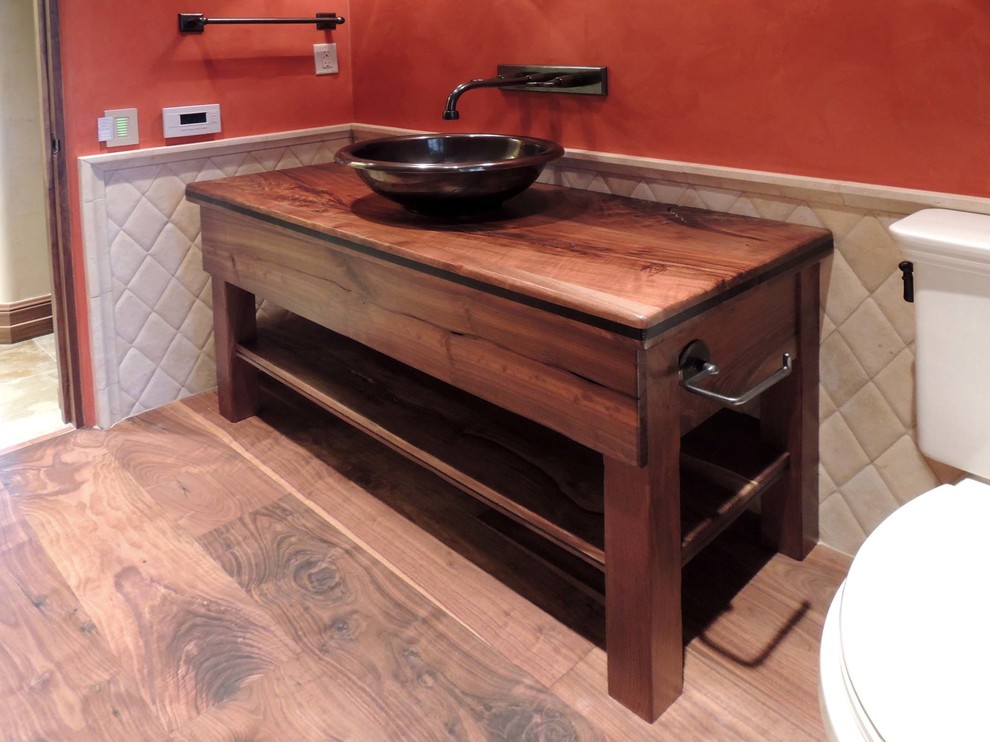 Photo of a small arts and crafts 3/4 bathroom in Other with a vessel sink, open cabinets, dark wood cabinets, wood benchtops, a two-piece toilet, medium hardwood floors, orange walls, white tile and porcelain tile.