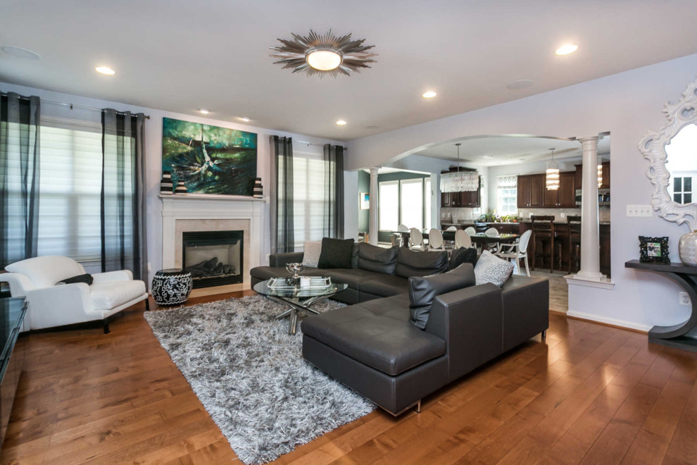 This is an example of a large contemporary open concept living room in Baltimore with blue walls, medium hardwood floors, a standard fireplace, a tile fireplace surround, a freestanding tv and brown floor.