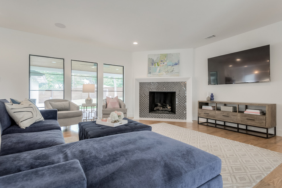 Transitional family room in Dallas with white walls, light hardwood floors, a standard fireplace, a tile fireplace surround and a wall-mounted tv.