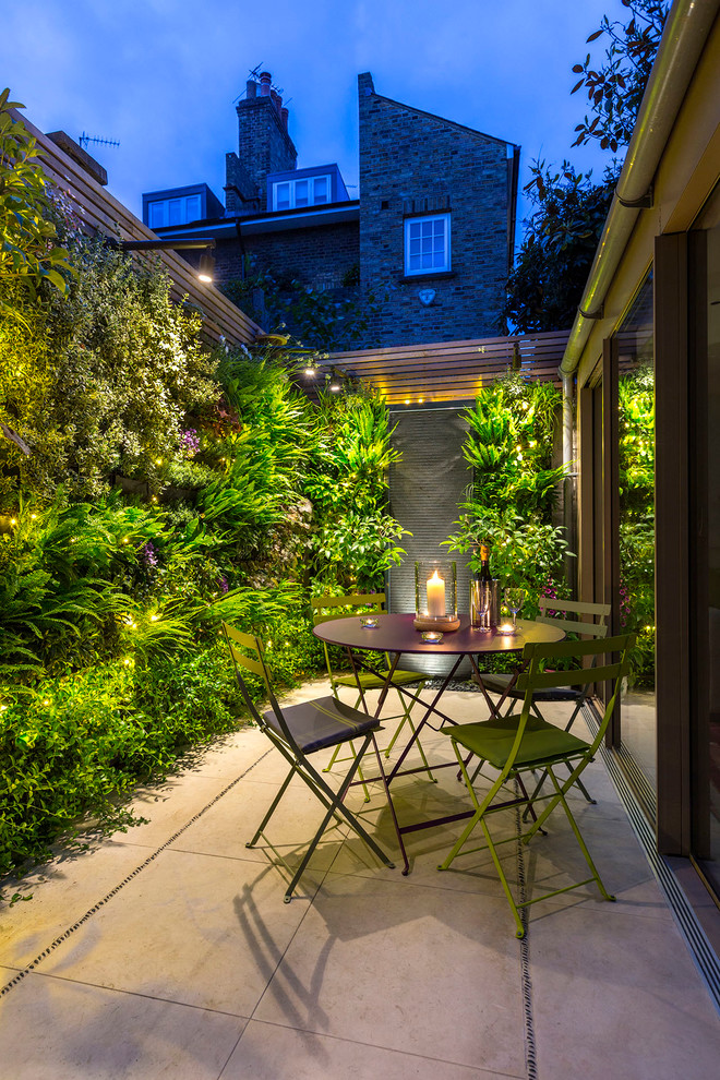 Inspiration for a small contemporary backyard patio in London with a vertical garden and natural stone pavers.