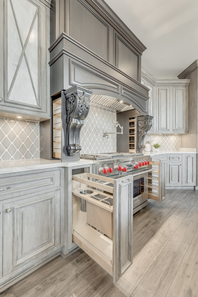 Inspiration for a large traditional u-shaped open plan kitchen in DC Metro with a farmhouse sink, raised-panel cabinets, distressed cabinets, granite benchtops, beige splashback, ceramic splashback, stainless steel appliances, dark hardwood floors, with island, grey floor and grey benchtop.