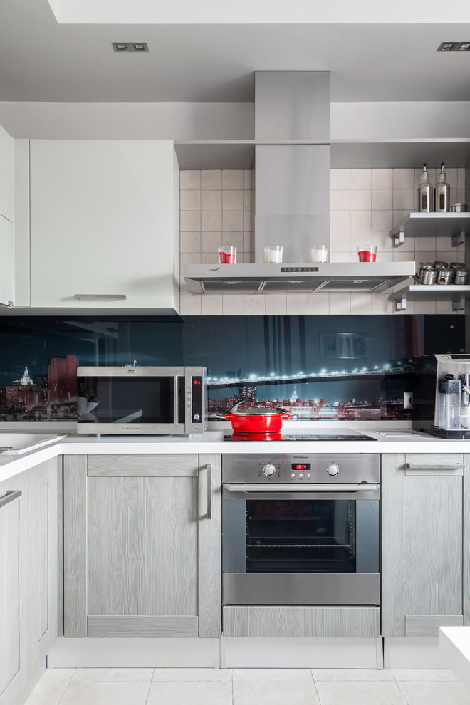 Small contemporary l-shaped kitchen in Moscow with a drop-in sink, shaker cabinets, grey cabinets, glass sheet splashback, stainless steel appliances and green splashback.