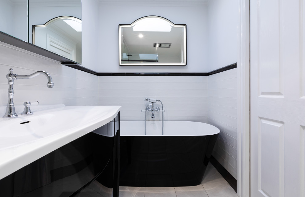 This is an example of a medium sized victorian ensuite bathroom in Sydney with recessed-panel cabinets, black cabinets, a freestanding bath, an alcove shower, a one-piece toilet, white tiles, ceramic tiles, white walls, cement flooring, an integrated sink, engineered stone worktops, grey floors, a hinged door, white worktops, an enclosed toilet, a single sink, a freestanding vanity unit and a vaulted ceiling.