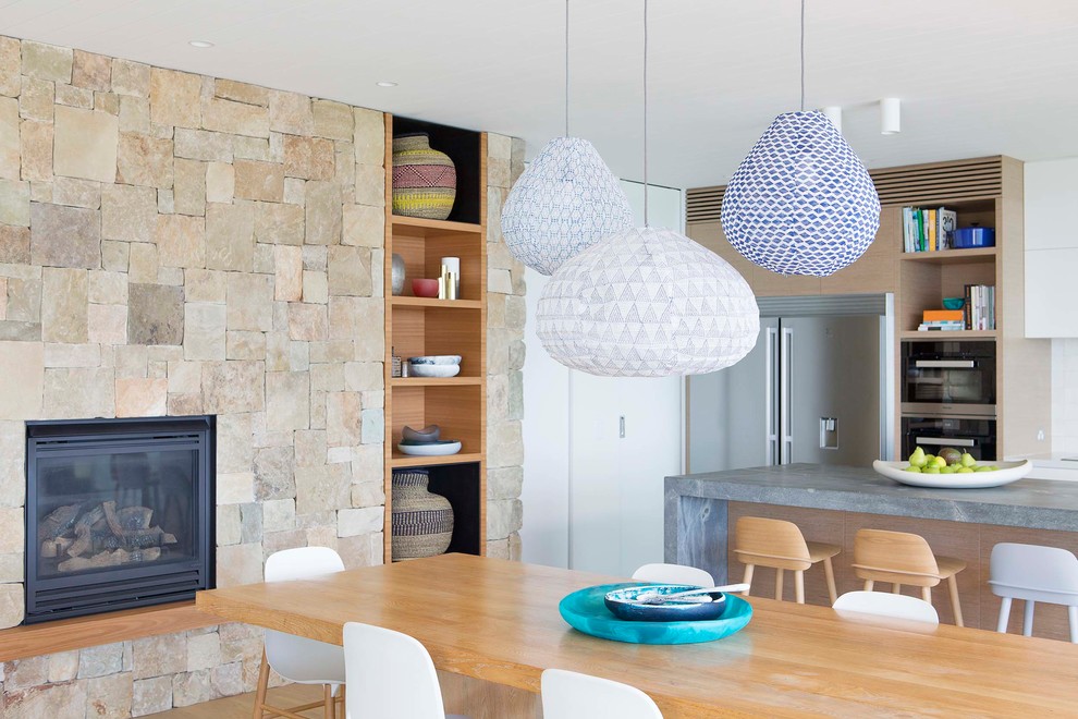 Inspiration for a large beach style galley open plan kitchen in Sydney with an undermount sink, flat-panel cabinets, white cabinets, quartz benchtops, white splashback, ceramic splashback, stainless steel appliances, light hardwood floors and with island.