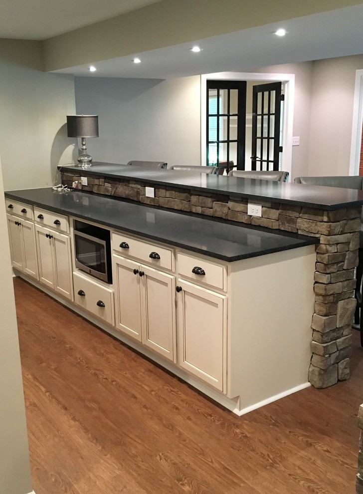 Basement - large walk-out vinyl floor basement idea with beige walls, a standard fireplace and a stone fireplace