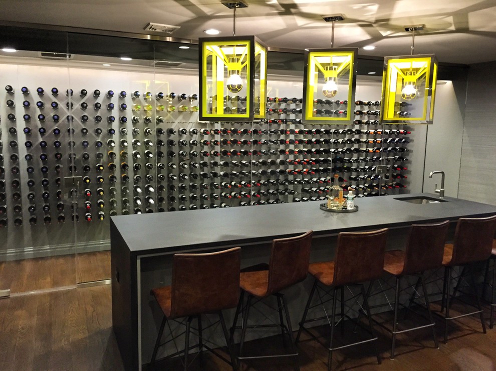 This is an example of a large modern wine cellar in New York with dark hardwood floors and display racks.