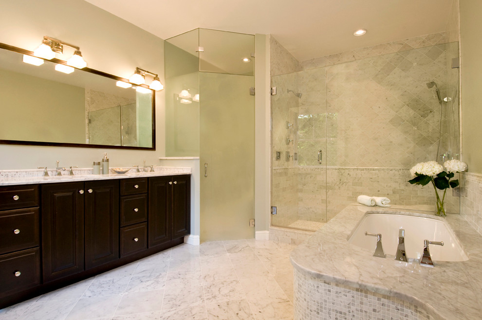 This is an example of a mid-sized transitional master bathroom in Boston with raised-panel cabinets, dark wood cabinets, an undermount tub, a corner shower, a one-piece toilet, gray tile, white tile, porcelain tile, grey walls, marble floors, an undermount sink, marble benchtops, grey floor and a hinged shower door.