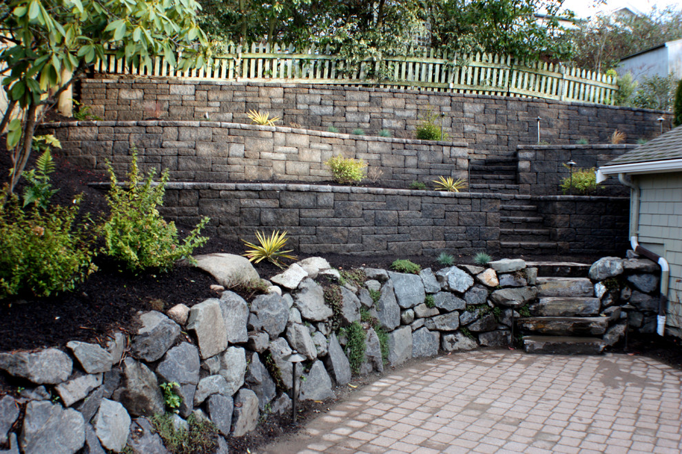 Design ideas for a mid-sized traditional backyard partial sun xeriscape for summer in Seattle with a retaining wall and concrete pavers.